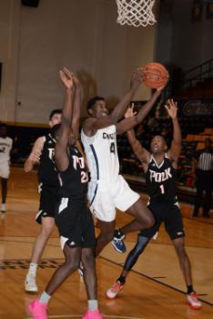 A Chipola basketball player attempts a layup surrounded by three Polk players.