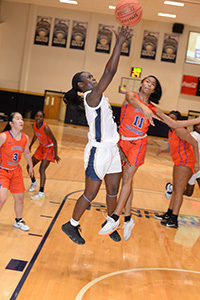 A Chipola basketball player shoots over a defender under the basket. 