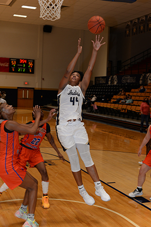 A Chipola Women's Basketball player goes up for a rebound flanked by members of the opposing team.