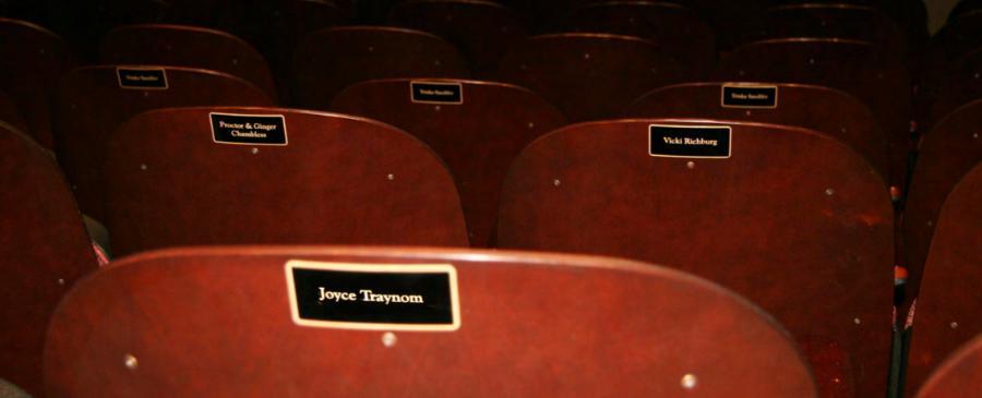 A view of the backs of theatre seats with engraves name plaques.