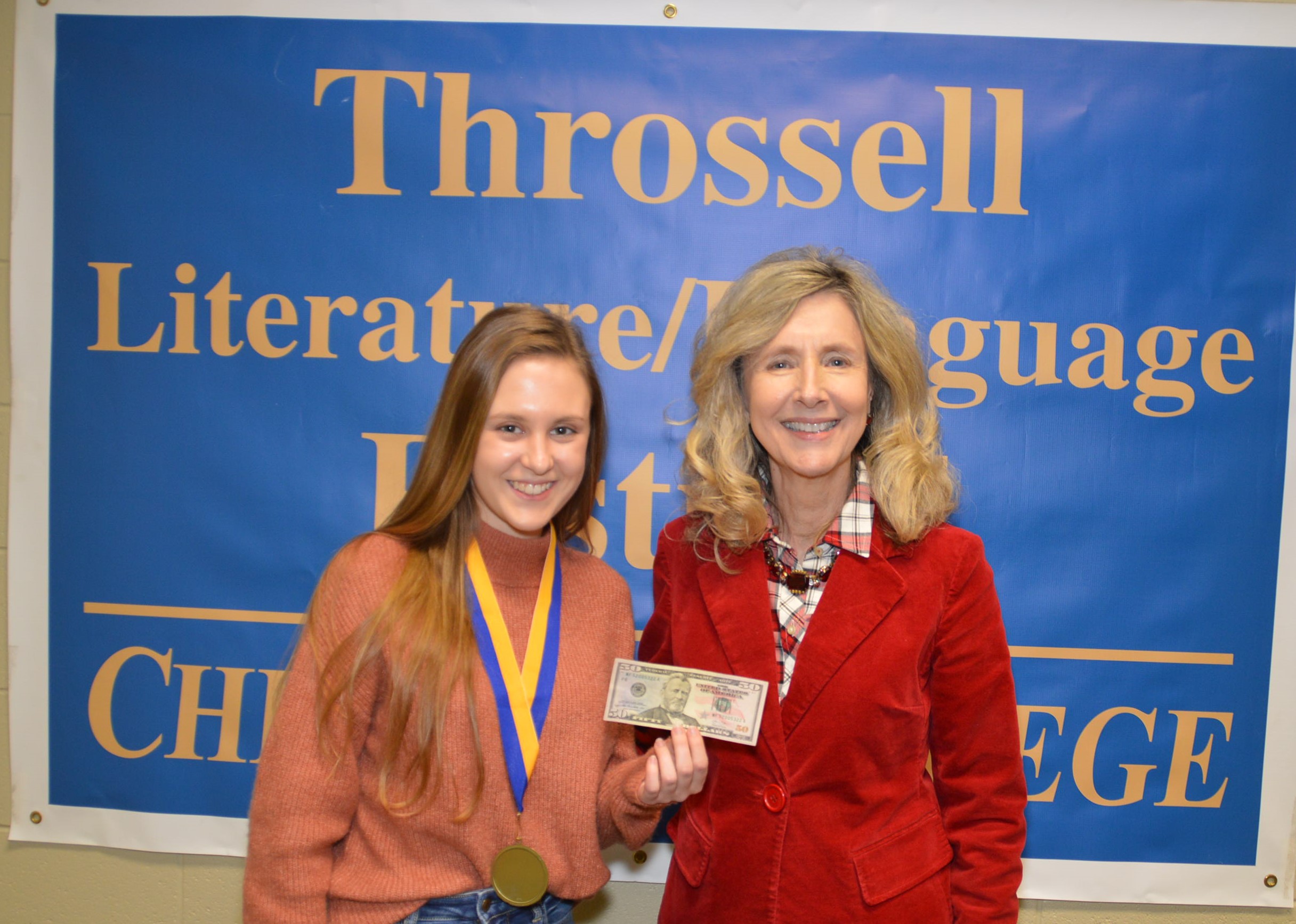 Dr. Sarah Clemmons congratulates a festival winner holding a trophy.