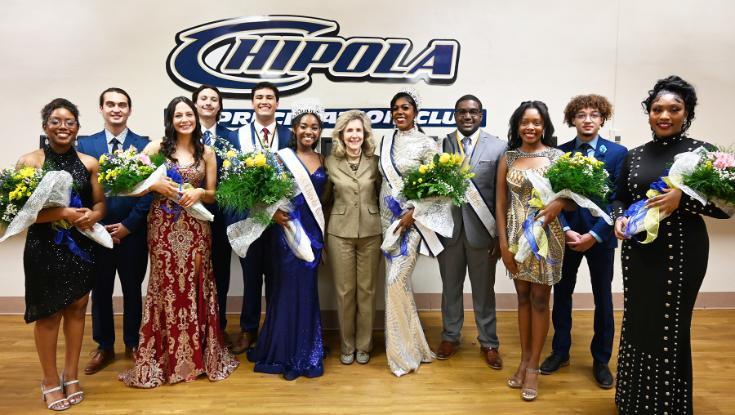 Picture of students on the homecoming court posing with college president at homecoming game